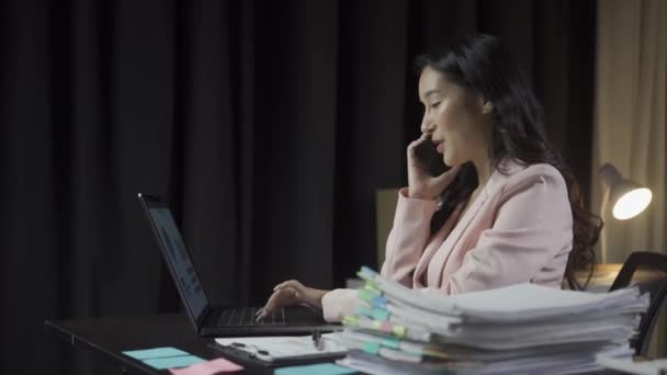 忙得不可开交的亚洲女商人用笔记本电脑在电话上与项目文件打交道 在现代办公室金融商业概念中遥不可及 — 图库视频影像