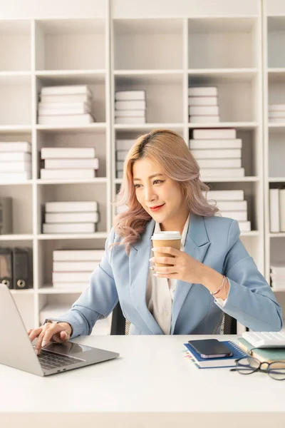 Asian female accountant working on laptop and calculating financial graph showing investment related results. Plan a successful business growth process. vertical image