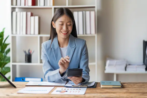 快乐的年轻亚洲女商人 带着财务文件 笔记本电脑和智能手机工作 — 图库照片