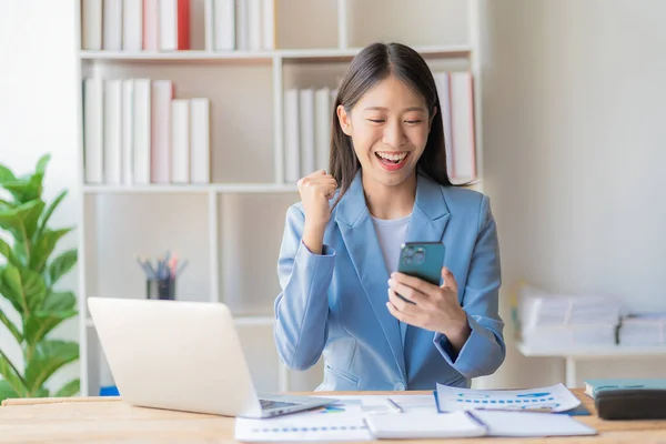 快乐的年轻亚洲女商人 带着财务文件 笔记本电脑和智能手机工作 — 图库照片