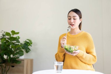 Güzel Asyalı kadın büyük bir gülümsemeyle salata yiyor gülen surat sağlıklı beslenme konsepti yüzü ve teni sağlıklı, taze ve parlak.