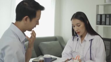 Beyaz laboratuvar önlüğü ve sınav eldivenleriyle gülümseyen güzel kadın dişçi, diş aletleri kullanıyor ve diş sağlığı kliniğinde diş modeli olan genç erkek hastayı muayene etmeye başlıyor..