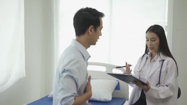 Joven Médico Asiático Uniforme Médico Blanco Utiliza Portapapeles Para Discutir — Vídeo de stock