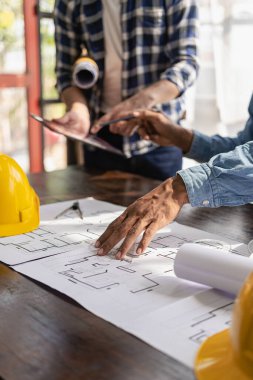 İki meslektaş, endüstriyel bir binadaki bir inşaat sahasındaki mimari bir proje hakkında veri ve dizüstü bilgisayar kullanmayı tartışıyorlar. Gayrimenkul projesi dikey resmi