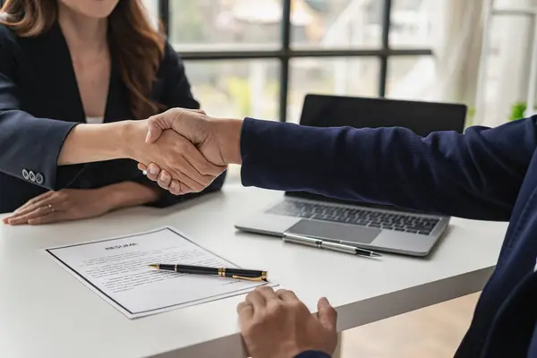 Executives shake hands with job applicants and read job applicant profiles to match the job positions. The company publishes online job vacancies to find people. human resources interview successful