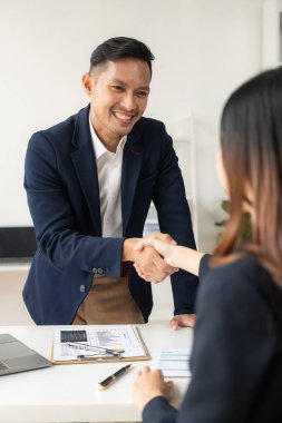 İki kendine güvenen Asyalı iş adamı iş görüşmesinde el sıkışıyor. Çağdaş ofis karşılama konseptinde selamlaşmalar ve işbirliği yapıyorlar. Dikey resim