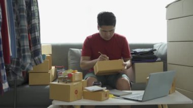 Evde bilgisayar ve tablet siparişlerini kontrol eden Asyalı erkek işadamı, KOBİ iş konsepti, çevrimiçi paket siparişi, 4K