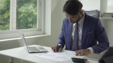 Finansal dökümanlar ve dizüstü bilgisayarlarla çalışan başarılı Afrikalı genç adam, yönetici ya da müşteri finansal belgeleri kontrol ediyor dizüstü bilgisayarla masada oturuyor.