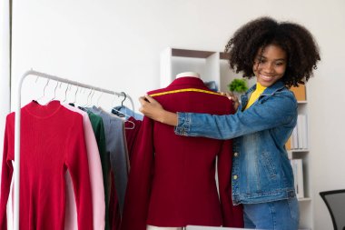 Afrikalı Amerikalı kız internetten canlı yayın yoluyla giysi sunar ve satar, şık bir giyim mağazası seçer. Moda tasarımcıları yeni koleksiyonların resimlerini çiziyor.