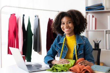Afrikalı Amerikalı kız internetten canlı yayın yoluyla giysi sunar ve satar, şık bir giyim mağazası seçer. Moda tasarımcıları yeni koleksiyonların resimlerini çiziyor.