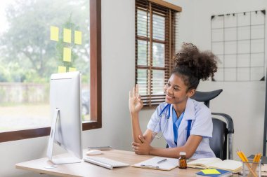 Ciddi bir Afrikalı doktor klinikte beyaz tıbbi önlük ve steteskop ile çalışıyor. Modern hastane Online Hasta Danışmanı Konsepti 'nde bilgisayar üzerinde çalışıyor.