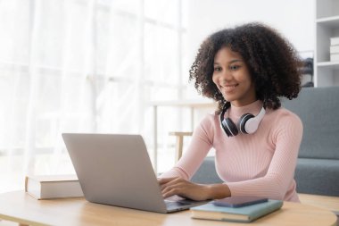 Kafede dizüstü bilgisayarla çalışan genç Afrikalı bir kadın. Millennial Afro-Amerikan kızı. Kulaklığı kafeteryada dizüstü bilgisayarla çalışıyor.