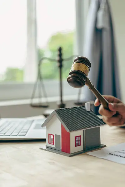 House auction concept: Judge holding a gavel to decide the house\'s sale at auction.