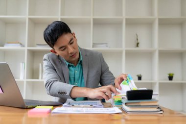 Ofiste bilgisayar ve belgelerle çalışan Asyalı işadamı iş yerinde çalışıyor, iş belgeleri, finansal planlama kavramları