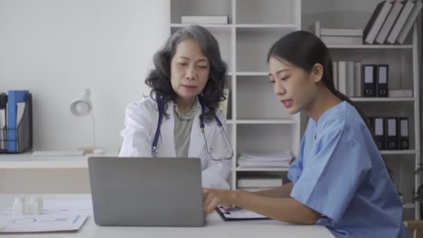 高齢の女性医師が 患者のさまざまな病気に関する病院観察室の医学生にアドバイスをしています — ストック動画