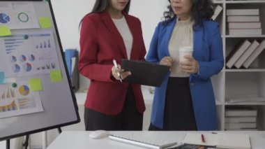 Yaşlı iş kadını ve genç Asyalı muhasebeci şirket maliyesi ve muhasebe işlerinden bahsediyorlar.