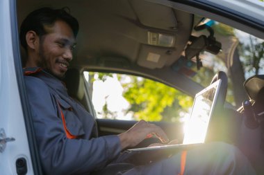 Otomobil tamircisi kontrol ve kontrol listesini panoya yazarak arabayı teftiş eder. Tamirci dizüstü bilgisayardaki araba parçaları stoğunu kontrol ediyor ve yol kenarındaki araba bozulmuş.