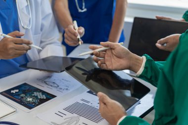 Sağlık ekipleri toplantılara dizüstü bilgisayarlarla katılır. Doktorlar ve çalışanlar belgeleri ve test sonuçlarını tartışıyor. Hastanelerdeki sağlık uzmanları yakın plan çekimde.