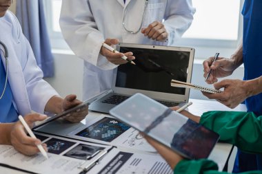 Sağlık ekipleri toplantılara dizüstü bilgisayarlarla katılır. Doktorlar ve çalışanlar belgeleri ve test sonuçlarını tartışıyor. Hastanelerdeki sağlık uzmanları yakın plan çekimde.