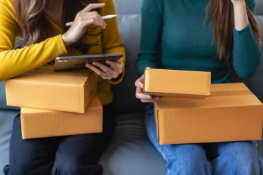 Başarılı bir iş kadını, internet üzerinden satış yaparken ve ev ofisinde paket teslimatı yaparken eğleniyor. Kadın, dizüstü bilgisayar ve KOBİ iş konseptini kontrol ediyor.