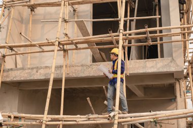 Mimarlar şantiyesindeki mimarlık projelerini tartışan iş arkadaşları inşaat projesi taslağı ve mimari planı için Mühendis ile birlikte inceleme sahasında çalışıyorlar.