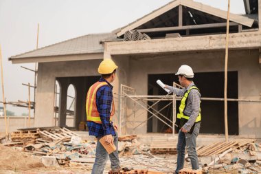 Mimarlar şantiyesindeki mimarlık projelerini tartışan iş arkadaşları inşaat projesi taslağı ve mimari planı için Mühendis ile birlikte inceleme sahasında çalışıyorlar.