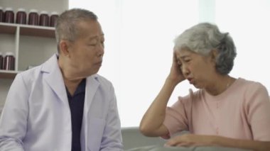 Profesyonel kıdemli erkek doktor hastanedeki yaşlı kadın hastaya danışmanlık yapıyor ve muayene ediyor. Rahatlamış atmosfer, sağlık, akıl sağlığı, yaşlılarla ilgilenme kavramı.
