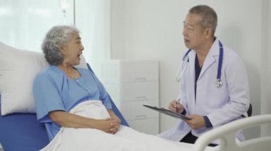 Profesyonel kıdemli erkek doktor hastanedeki yaşlı kadın hastaya danışmanlık yapıyor ve muayene ediyor. Rahatlamış atmosfer, sağlık, akıl sağlığı, yaşlılarla ilgilenme kavramı.