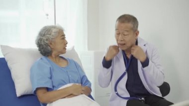Profesyonel kıdemli erkek doktor hastanedeki yaşlı kadın hastaya danışmanlık yapıyor ve muayene ediyor. Rahatlamış atmosfer, sağlık, akıl sağlığı, yaşlılarla ilgilenme kavramı.