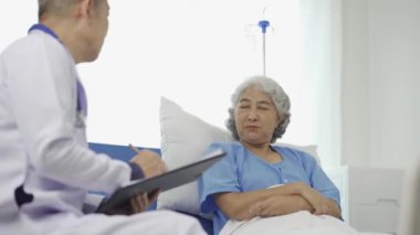 Profesyonel kıdemli erkek doktor hastanedeki yaşlı kadın hastaya danışmanlık yapıyor ve muayene ediyor. Rahatlamış atmosfer, sağlık, akıl sağlığı, yaşlılarla ilgilenme kavramı.