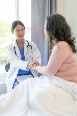 Asyalı kadın doktor, hastanede hastayı cesaretlendirmek için gülümseyen bir hastayla konuşuyor. Yaşlı bir Asyalı kadın, hastane ofisindeki bir doktoru ziyaret ediyor. Sağlık muayenesinin sonuçları hakkında konuşalım.