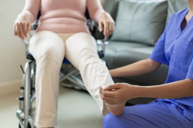 Asyalı kadın fizyoterapisti olan yaşlı bir kadın hasta. Kolunu fizik tedavi için tutuyor. Zayıf kasları tedavi ediyor. Hastanenin muayene odasında bu egzersizi yapmaya niyetli bir hasta görülüyor..