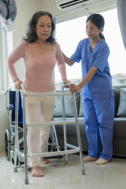 Asyalı kadın fizyoterapisti olan yaşlı bir kadın hasta. Kolunu fizik tedavi için tutuyor. Zayıf kasları tedavi ediyor. Hastanenin muayene odasında bu egzersizi yapmaya niyetli bir hasta görülüyor..