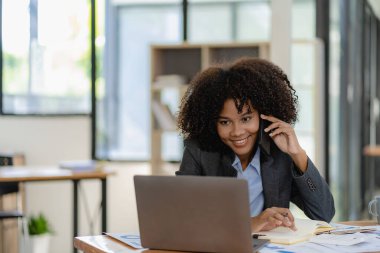 Ofiste çalışan iş kadını müşterilerle bağlantı kuruyor, iletişim kuruyor ve sohbet ediyor. Profesyonel kadın iletişim ağı ve iletişim için akıllı telefonlu bir masa planlıyor