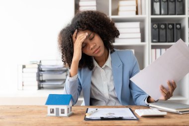 Afrikalı Amerikalı kız elinde emlakçı ya da banka veznedarı, sigorta konsepti ile arazi kredisi imzalamak için anlaşma belgelerini okumak üzere kalem tutuyor.