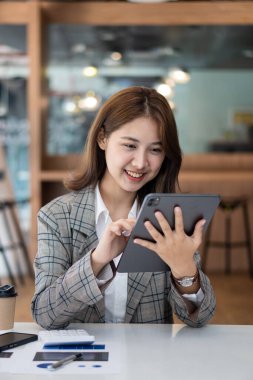 Finans ofisinde çalışan genç Asyalı muhasebeci, hesap makinesi kullanarak satış raporlarını yönetiyor, rapor hazırlıyor, hesap bakiyeleri, belgeler, vergi denetimi yapıyor. dikey resim