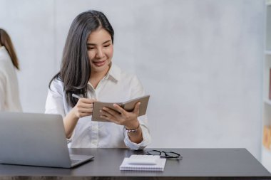 Finans ofisinde çalışan genç Asyalı muhasebeci, hesap makinesi kullanarak satış raporlarını yönetiyor, rapor hazırlıyor, hesap bakiyeleri, belgeler, vergi denetimi yapıyor. dikey resim