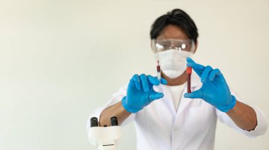 Bilim adamları laboratuarda laboratuvar teknisyenlerinde araştırma için test tüpleri tutan mavi porsuk kimyasalı örneği aldı.