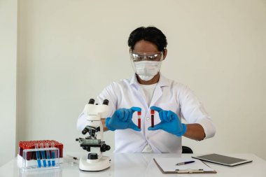 Bilim adamları laboratuarda laboratuvar teknisyenlerinde araştırma için test tüpleri tutan mavi porsuk kimyasalı örneği aldı.