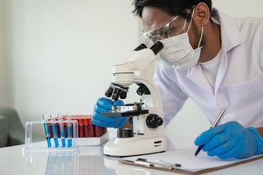 Bilim adamları laboratuarda laboratuvar teknisyenlerinde araştırma için test tüpleri tutan mavi porsuk kimyasalı örneği aldı.