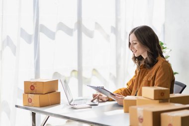 Online küçük işletme sahibi Young Girişimci, çevrimiçi küçük işletme, evde dizüstü bilgisayar ve kutularla çalışıyor. Paketleme ve nakliye durumları, KOBİ iş kavramları