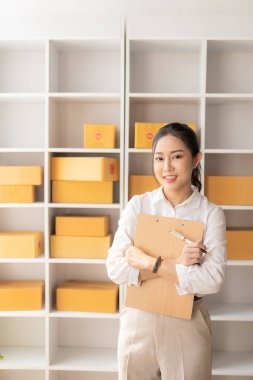 Müşteriyle akıllı telefondan konuşan Asyalı kadın, dizüstü bilgisayar, küçük işletme, e-ticaret ve çevrimiçi alışveriş, küçük ve yeni girişimci, perakende sektörü, KOBİ