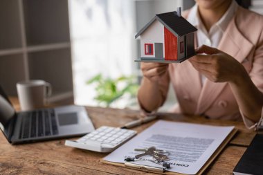 Asyalı kadın satış temsilcilerine yakın ev modelleri yeni yerlerdeki masalarda fiyatlar ve kiralama veya kiralama koşulları sunuyor. Kontratı imzala