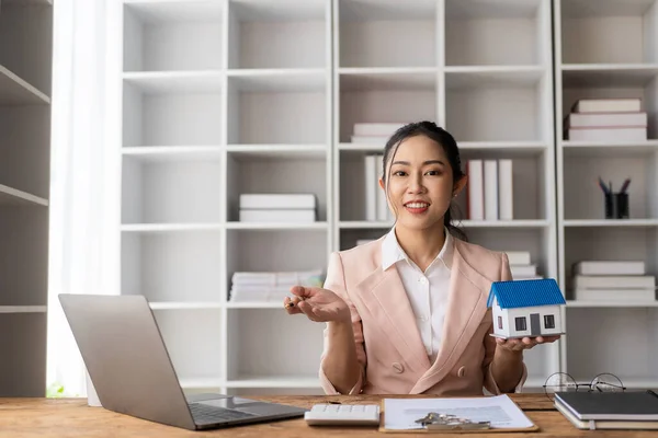 House models near Asian female sales representatives offer prices and conditions for purchase or rental on desks in new locations. Sign the contract