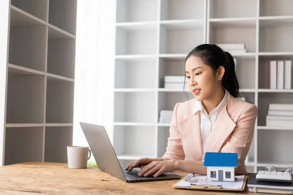 House models near Asian female sales representatives offer prices and conditions for purchase or rental on desks in new locations. Sign the contract