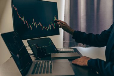 Borsa tablosuna bakan borsa simsarı, yatırım stratejisini analiz ediyor, hisse senedi grafikleri ve göstergelerle monitör ekranı ile çalışıyor, risk kararları almak için çok çalışan insanlar.