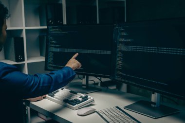 Ofisteki beyaz masadaki masaüstü bilgisayarında çalışan erkek programcı, ağ, kötü amaçlı yazılım veya ofis yazılımı için taklit dizüstü bilgisayarda kodlama yapıyor.
