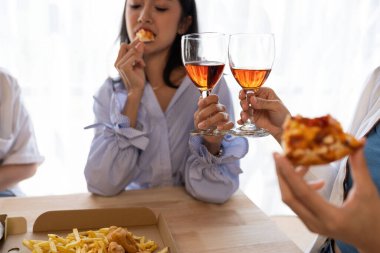Bir grup Asyalı bayan arkadaş bir partide birlikte eğleniyorlar. Pizza partisi şarabı önemli bir anı kutluyor.