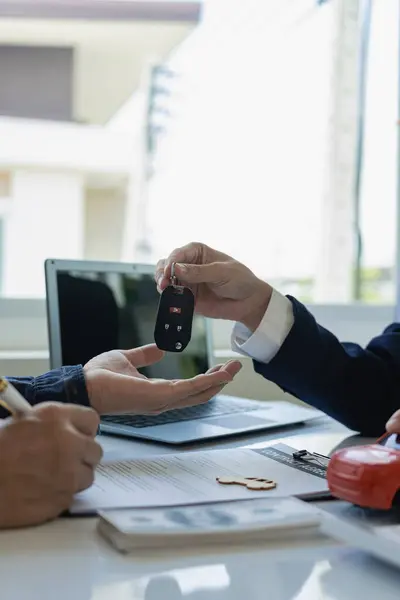Car sales representative gives keys to new car owner, concept for car rental Focus on the key. Pick up the key. Close-up of the key transfer from the new machine to the buyer.