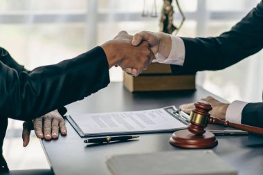 Bir avukat, anlaşmanın sözleşmeli şartlarını görüşmek üzere bir avukatla anlaşma yapmak için bir işadamıyla tokalaşıyor. Kontratta. Yakın plan fotoğraf..